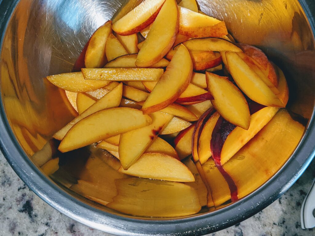 sliced peaches in a silver bowl